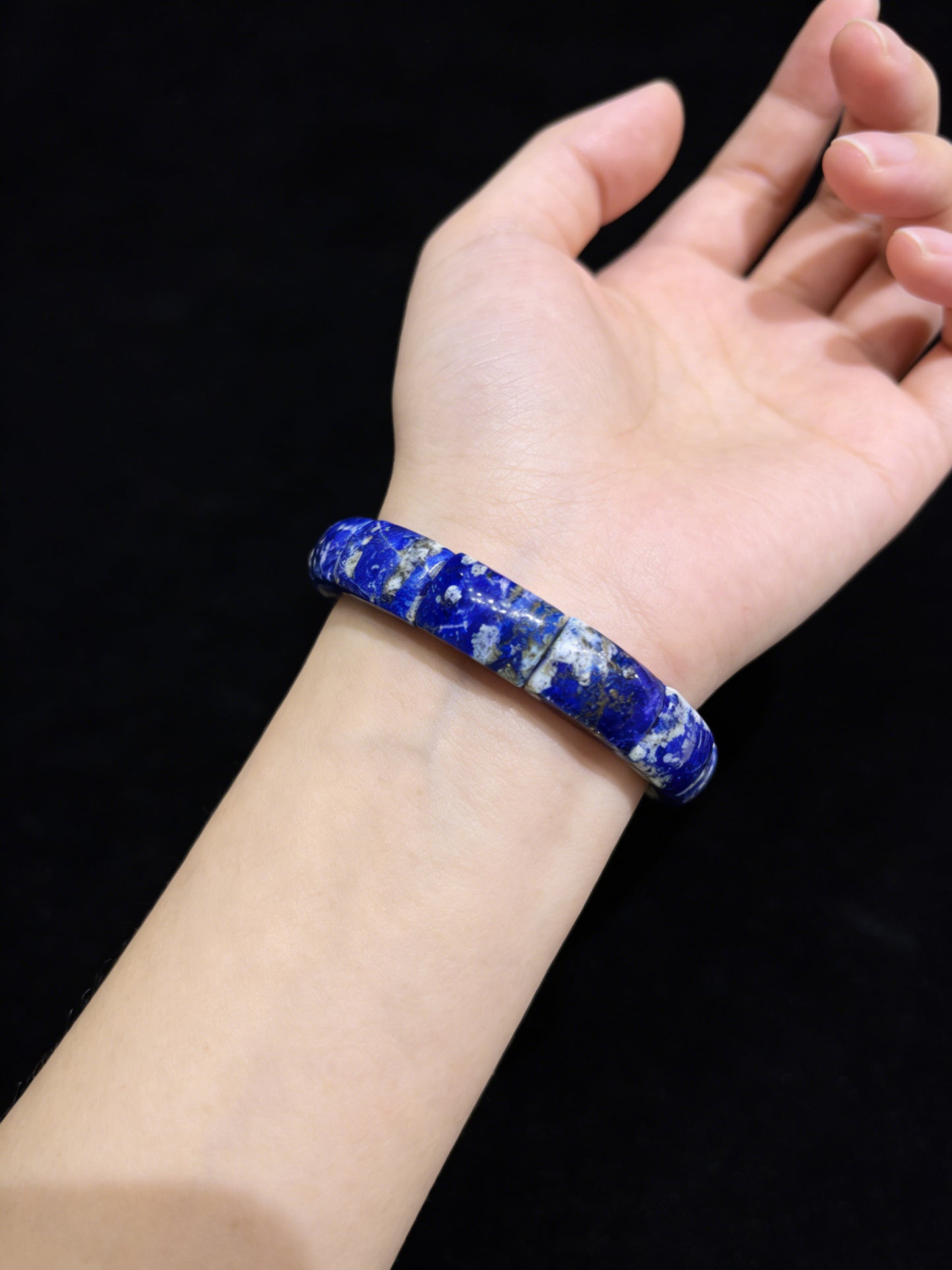 Woman wearing natural lapis lazuli square bead bracelet; deep blue gemstone jewelry for mindful presence and style
