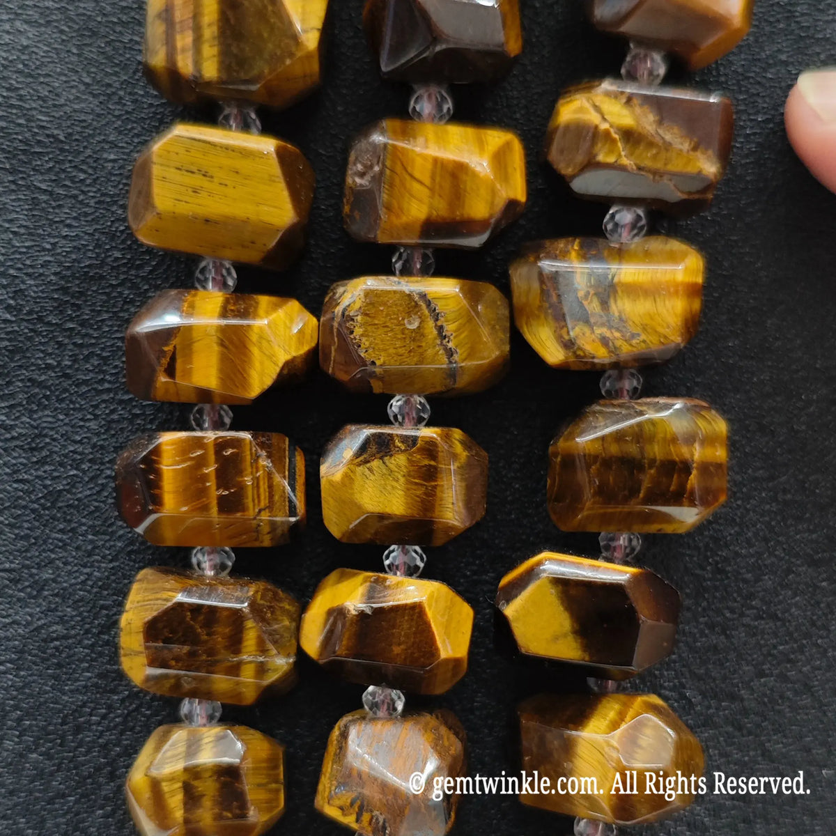 Close up view of natural golden tiger eye freeform faceted nugget beads highlighting chatoyant optical sheen