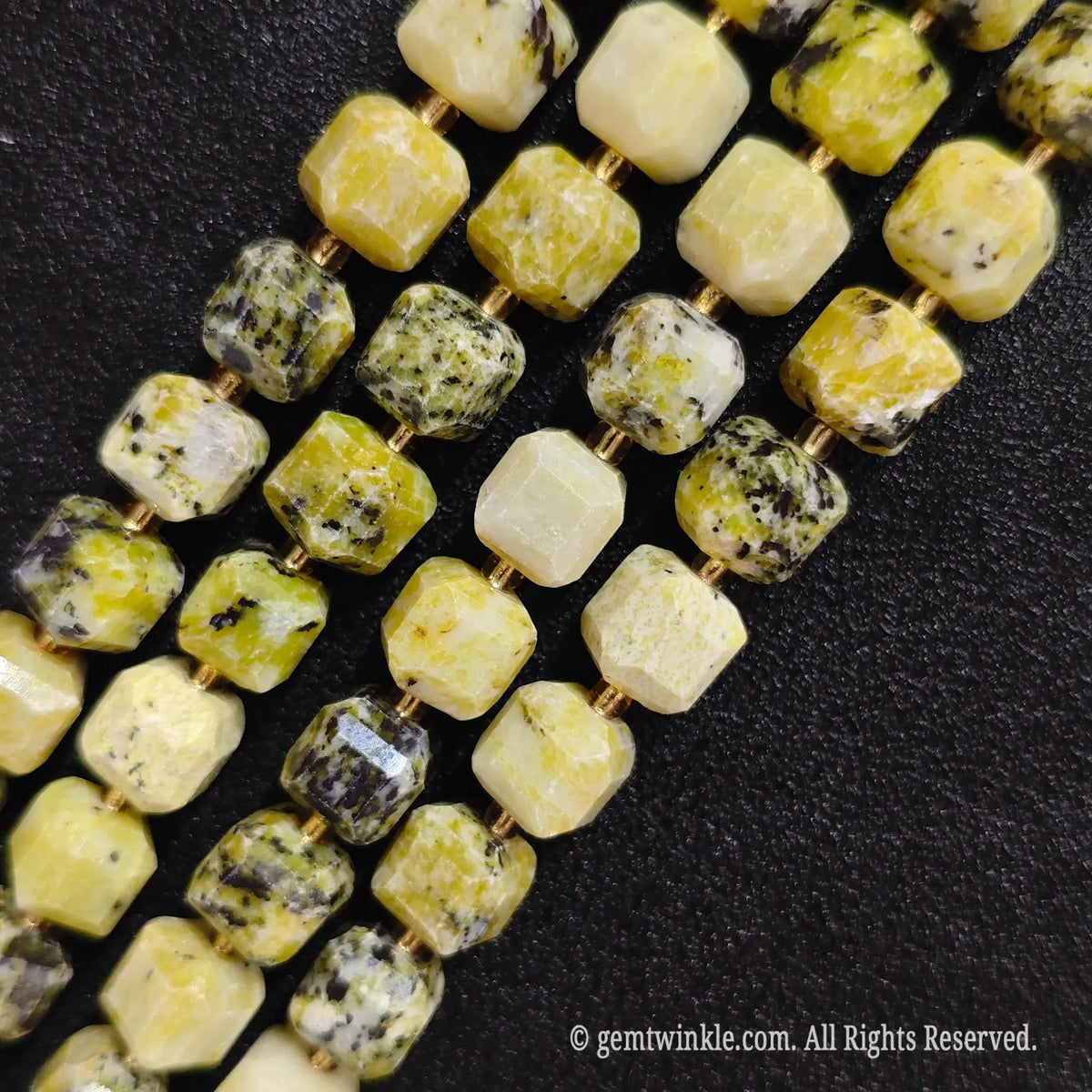 Multiple parallel strands of natural yellow jasper soft-tumbled cube beads viewed from distance