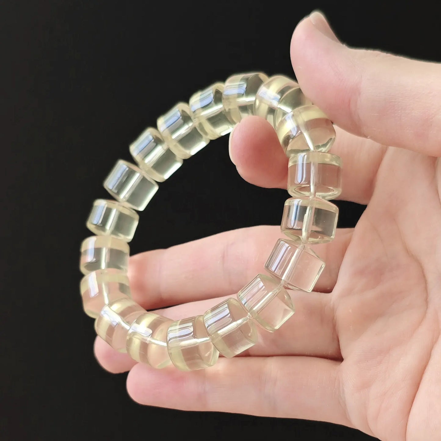 Natural lemon-yellow citrine wheel beads, ~14mm width, polished smooth, stretch elastic—displayed on hand against black background