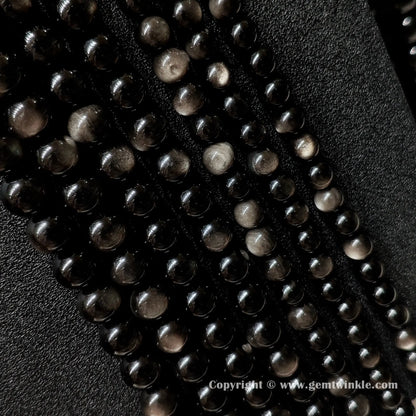 Parallel rows of Grade A silver sheen obsidian round bead strands demonstrating size range from 6mm up to 16mm