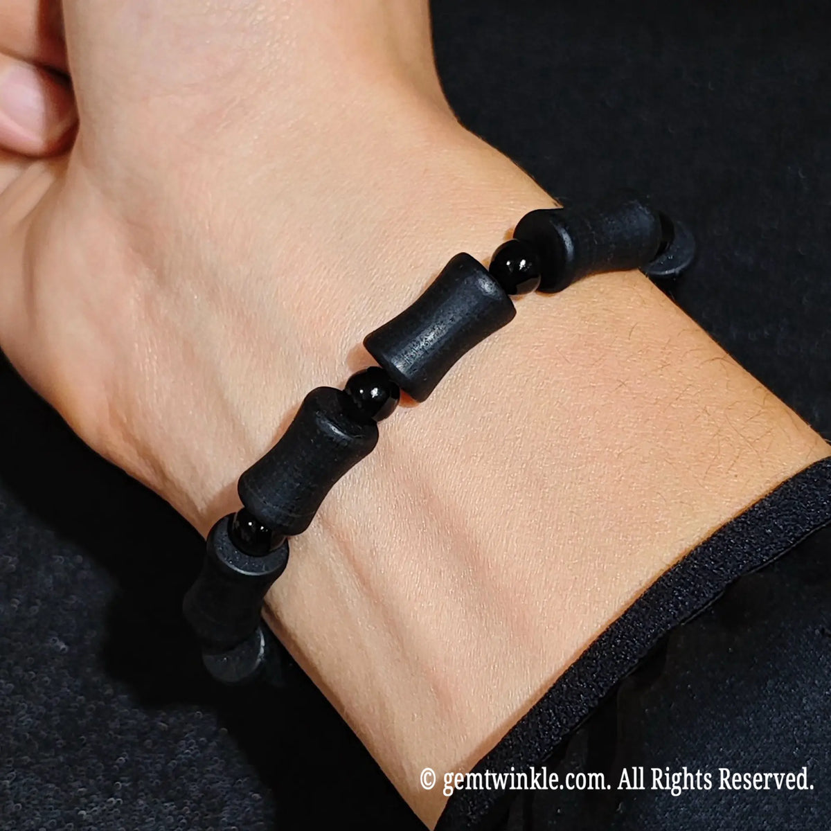 Natural matte black tourmaline barrel stretch bracelet worn on wrist highlighting gothic aesthetic and dark stone texture