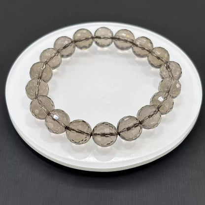 Clean presentation: uniformly faceted smoky quartz beads strung on elastic cord—no metal, no spacers, pure stone