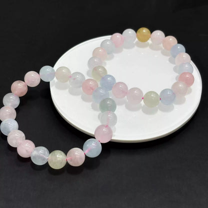 Two loops of natural morganite bracelet on white ceramic dish against black backdrop, showcasing soft pink-blue-green tones.
