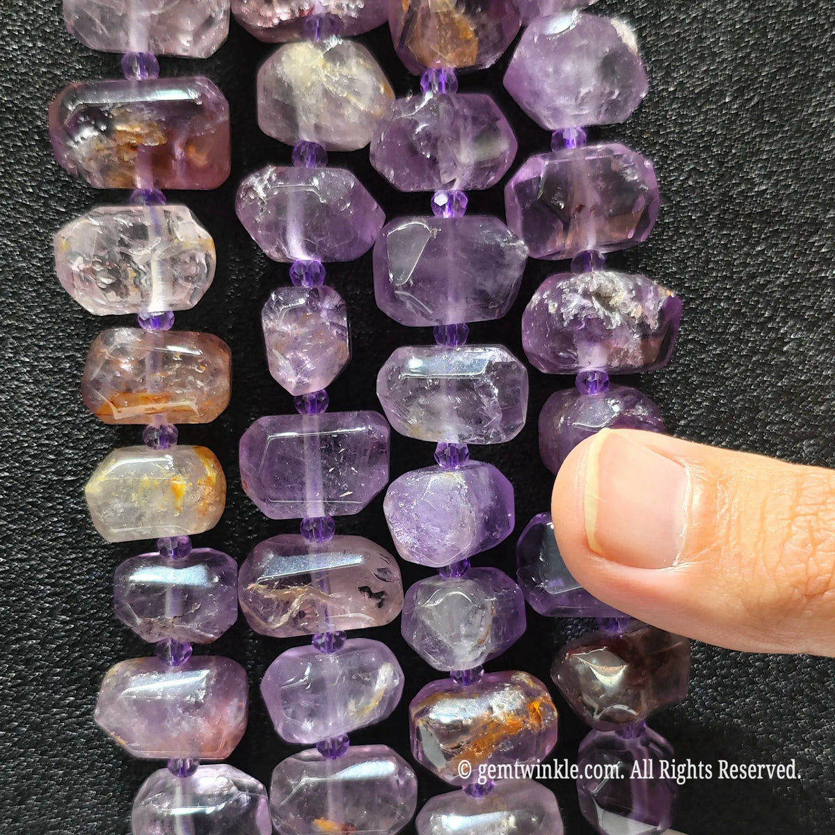Close up of multiple strands of unpolished style irregular freeform amethyst phantom quartz beads for DIY jewelry supplies