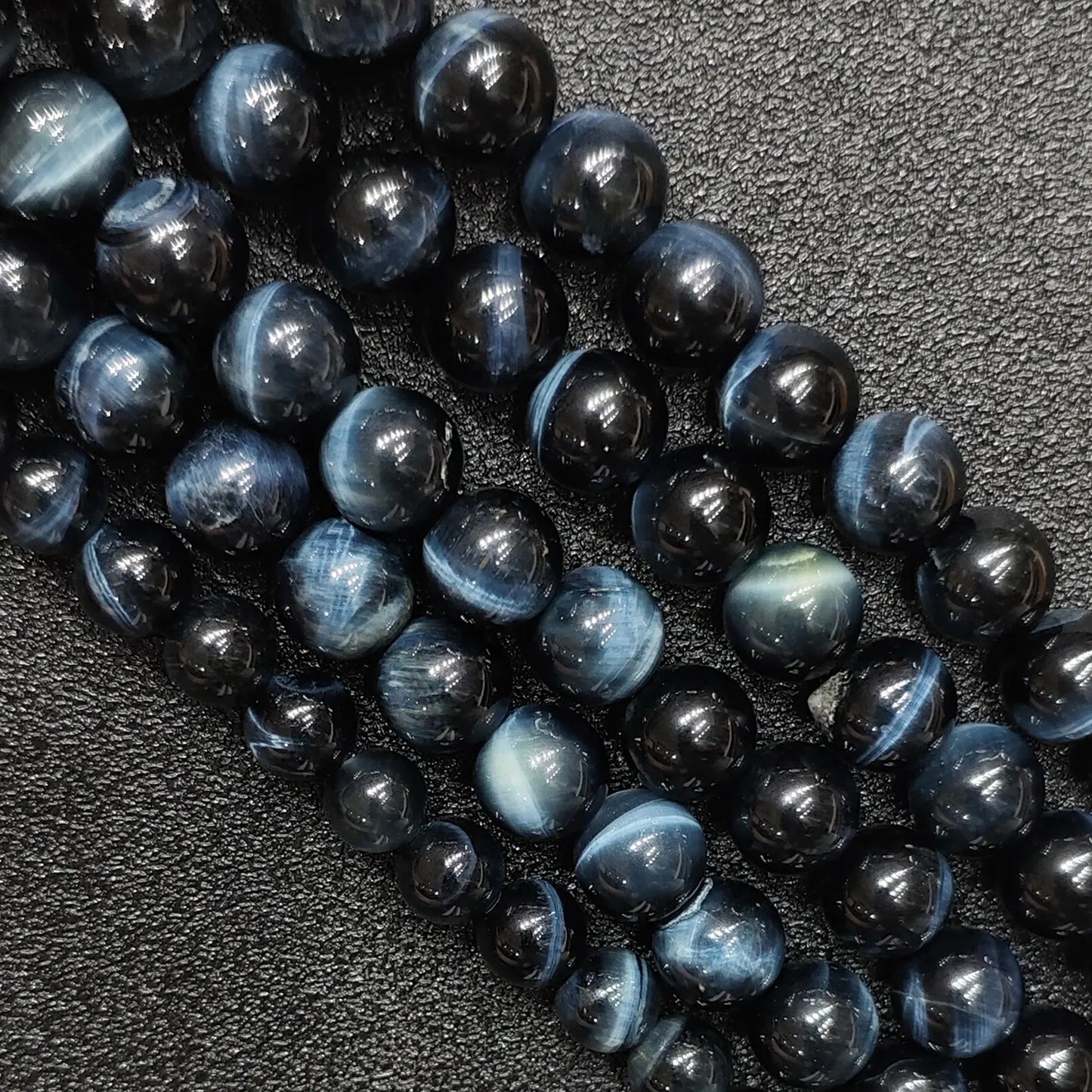 Close up of natural blue tigers eye gemstone beads showing strong cat eye chatoyancy