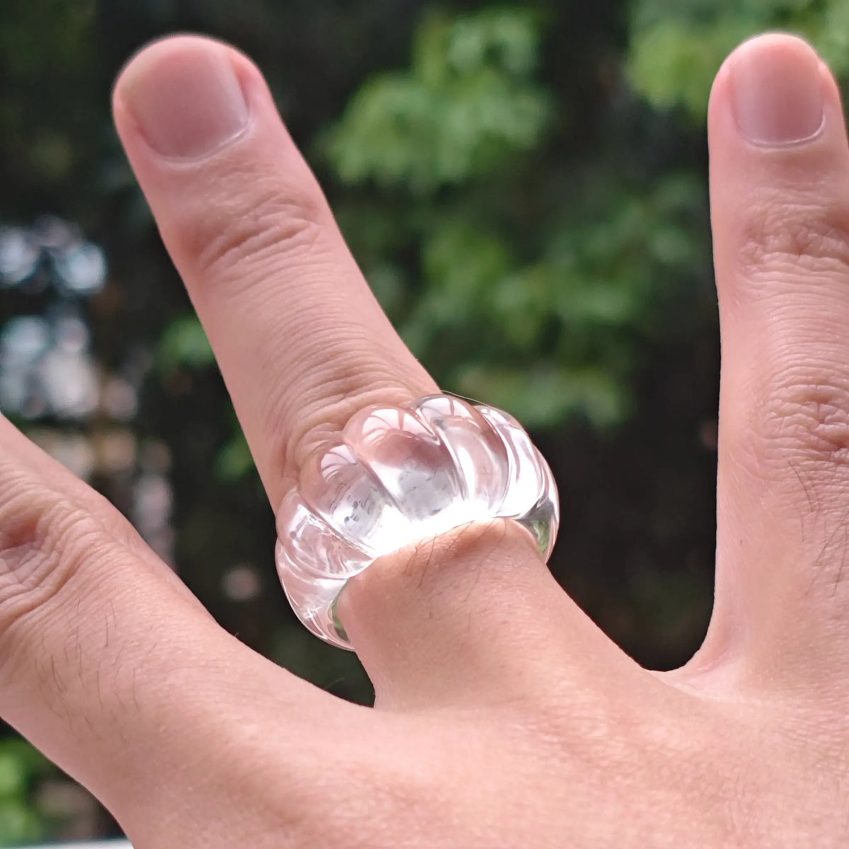 Solid carved fluted natural clear quartz ring worn on hand showing ribbed texture and mirror polish