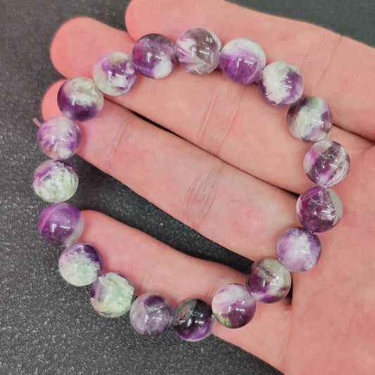Natural feather fluorite round bead bracelet displayed on hand showing purple and green cloud inclusions