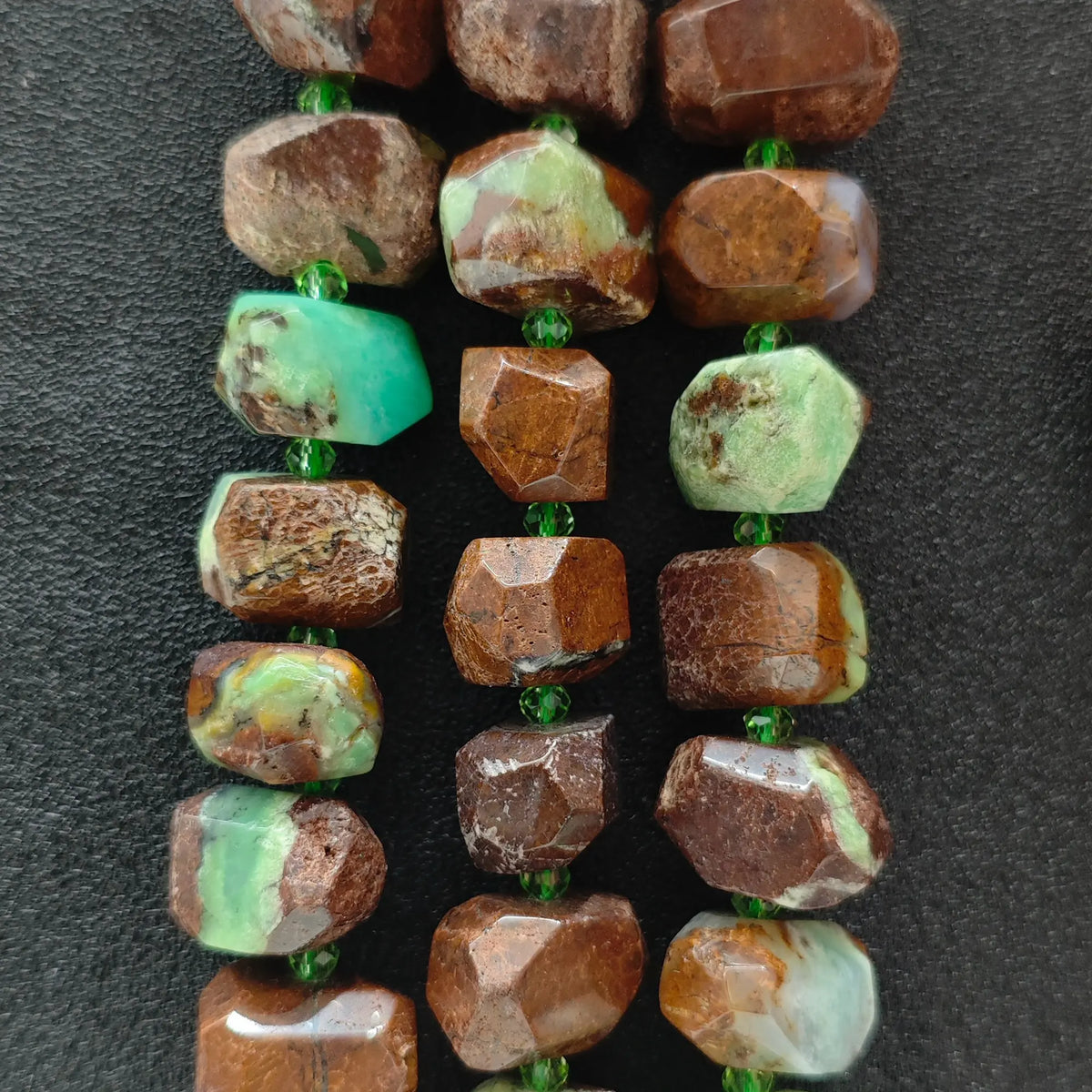 Strands of natural green jasper cut nugget beads displaying vivid green chalcedony in brown ironstone matrix on dark background