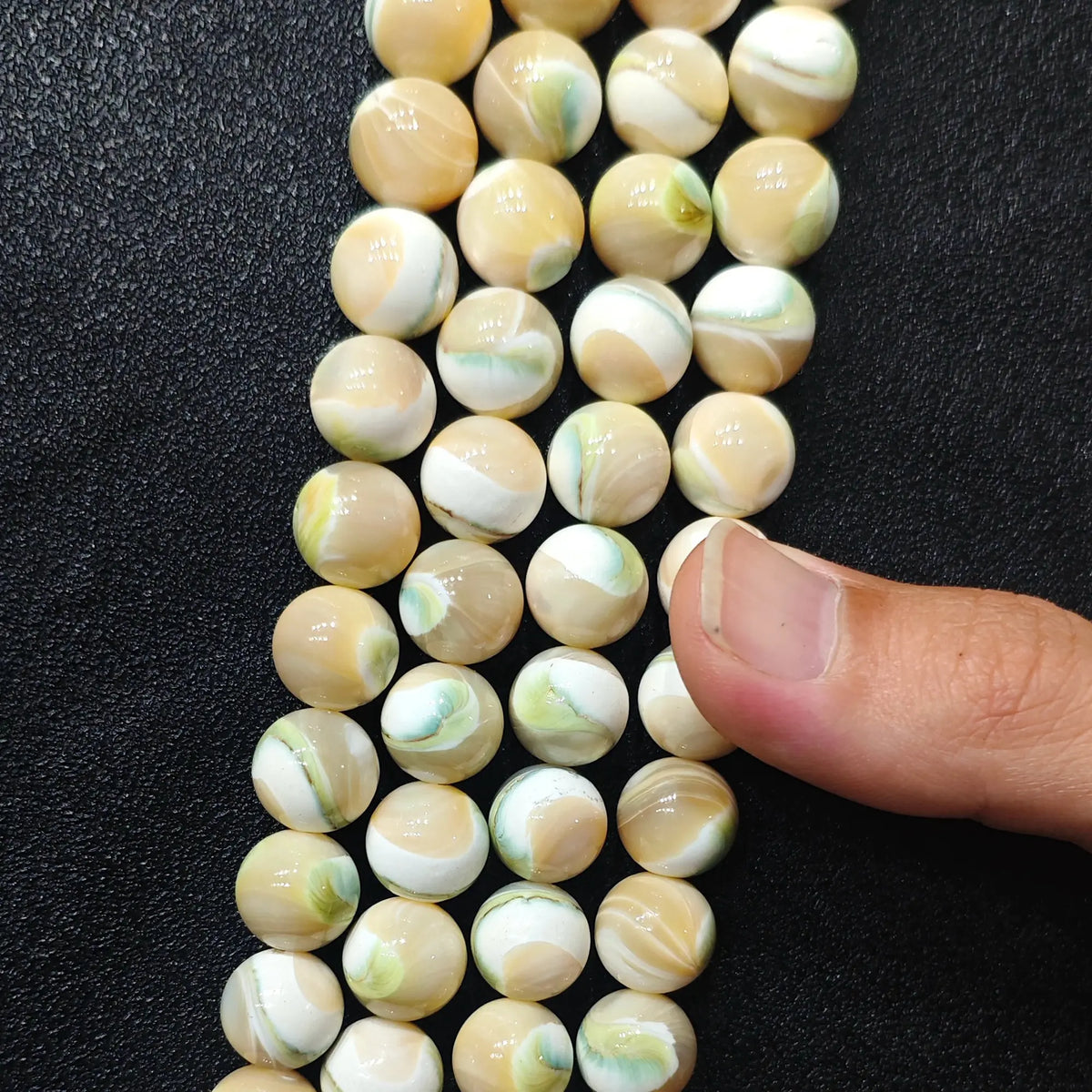Multiple strands of natural green swirl shell round beads showcasing creamy ivory tone and subtle sea green spirals