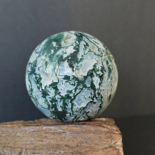 Natural moss agate sphere (approx. 6.5cm), D variant with vivid green dendritic inclusions on milky white chalcedony; displayed on natural wood base for altar or desk decor