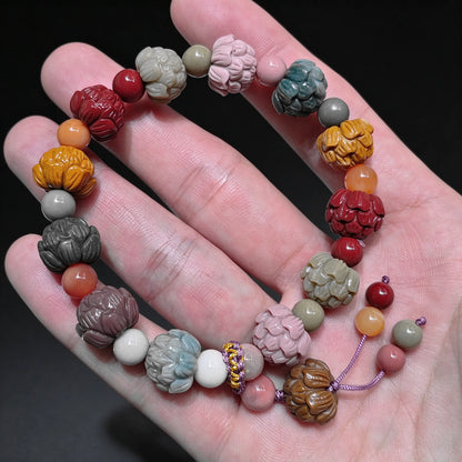 Palm displaying a natural multi color Alxa agate carved lotus bead bracelet featuring red yellow green and pink lotus carved beads