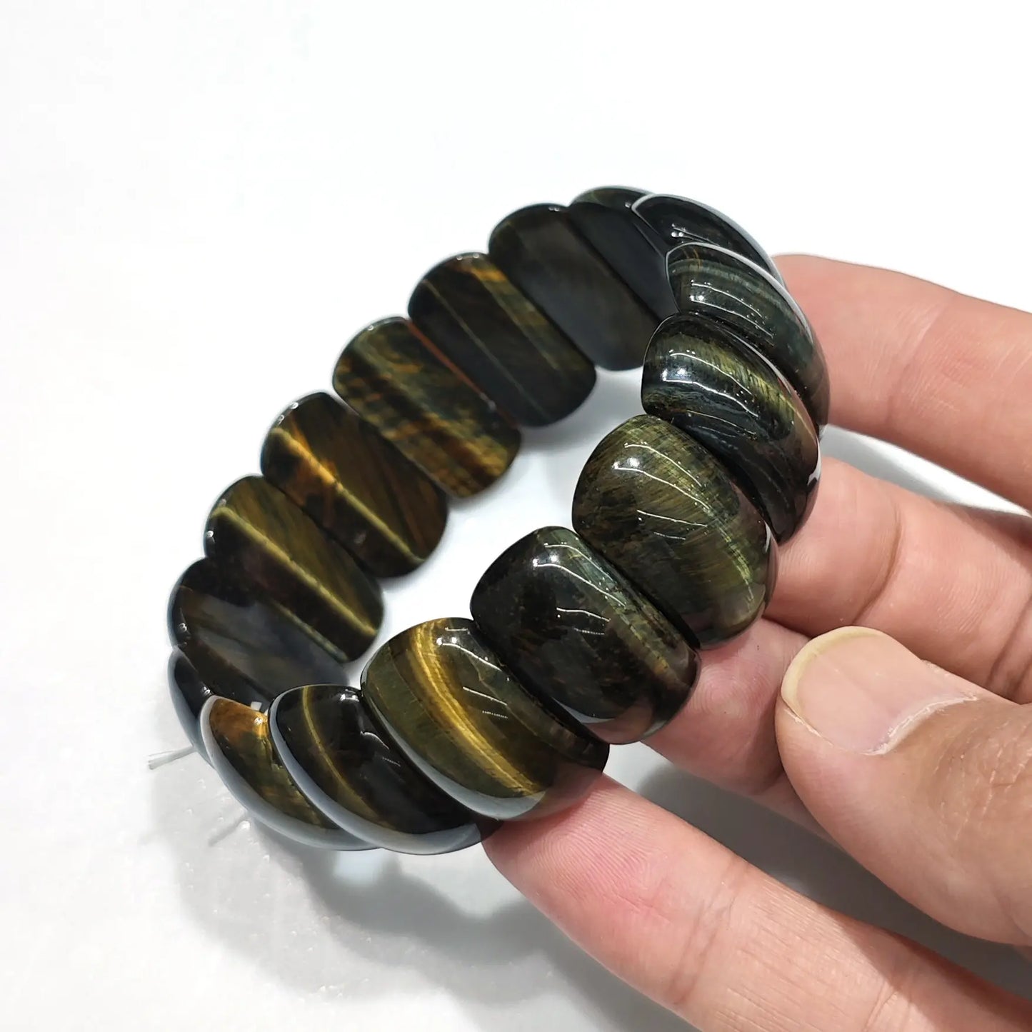 Hand holding natural multicolor tiger eye elastic bracelet with 25mm beads (red, yellow, blue, black bands), displayed on 18cm wrist — unisex fit for wholesale resale