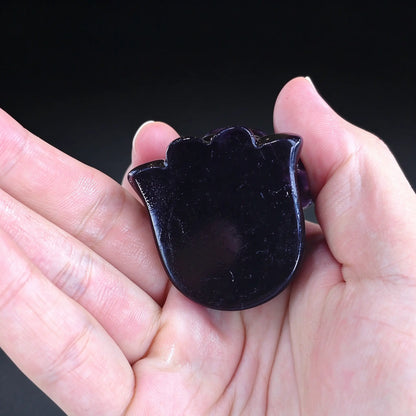 Palm displaying the flat bottom base of a natural purple fluorite carved lucky elephant mini statue