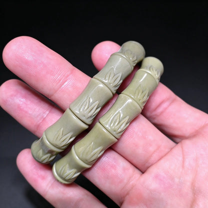Palm displaying two natural sage green Alxa agate carved bamboo joint stretch wristbands highlighting porcelain polish