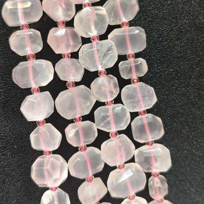 Strands of natural translucent rose quartz faceted freeform beads displaying soft pink ice-crystal luster on dark background