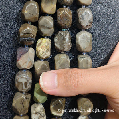 Strands of natural volcanic ash agate freeform beads aligned on dark background showing earth tone variations