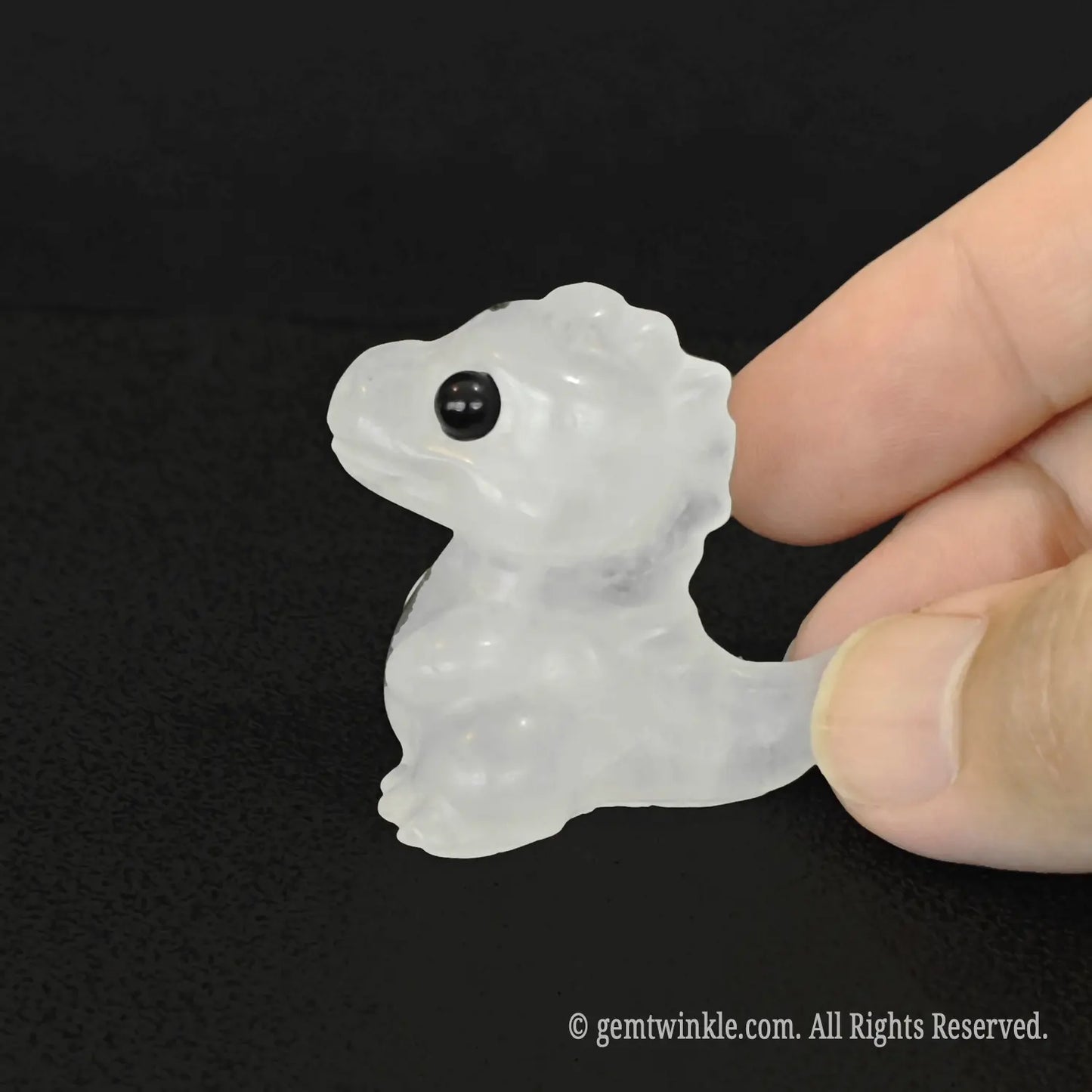 Natural clear quartz rock crystal baby dinosaur mini carving held in hand demonstrating mineral clarity and texture