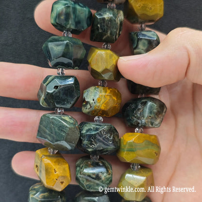 Close up perspective of multiple natural ocean jasper faceted chunky bead strands showing earthy variegated colors