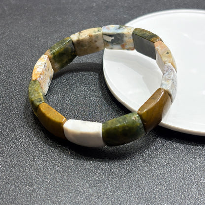 Close-up of natural ocean jasper bracelet showing concentric banding, smooth edges, and mixed green-white-brown coloration