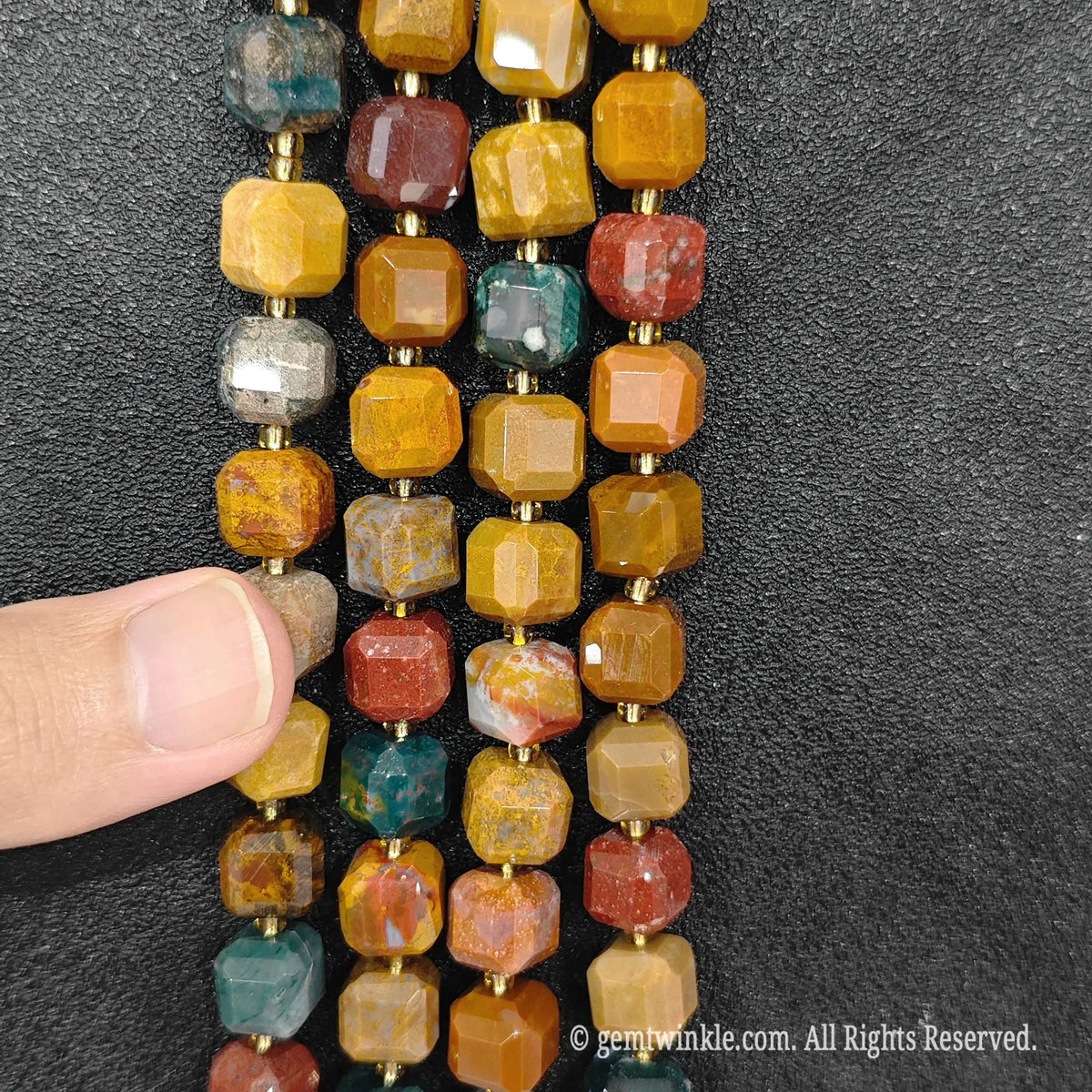 Multiple parallel strands of natural ocean jasper soft-tumbled cube beads viewed from distance