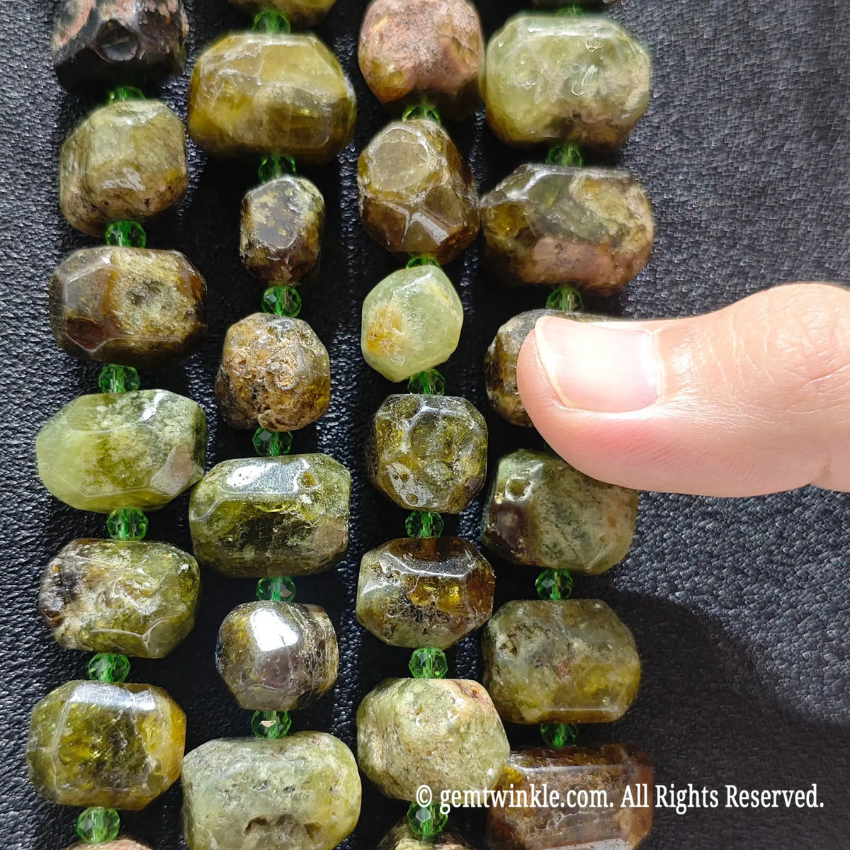 Close up perspective of multiple natural green garnet faceted freeform bead strands showing polished vitreous finish