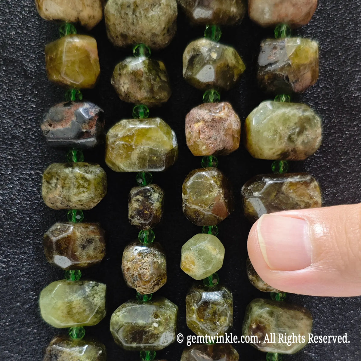 Hand holding three strands of natural green garnet faceted freeform beads showing rich olive green crystal matrix