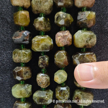 Hand holding three strands of natural green garnet faceted freeform beads showing rich olive green crystal matrix