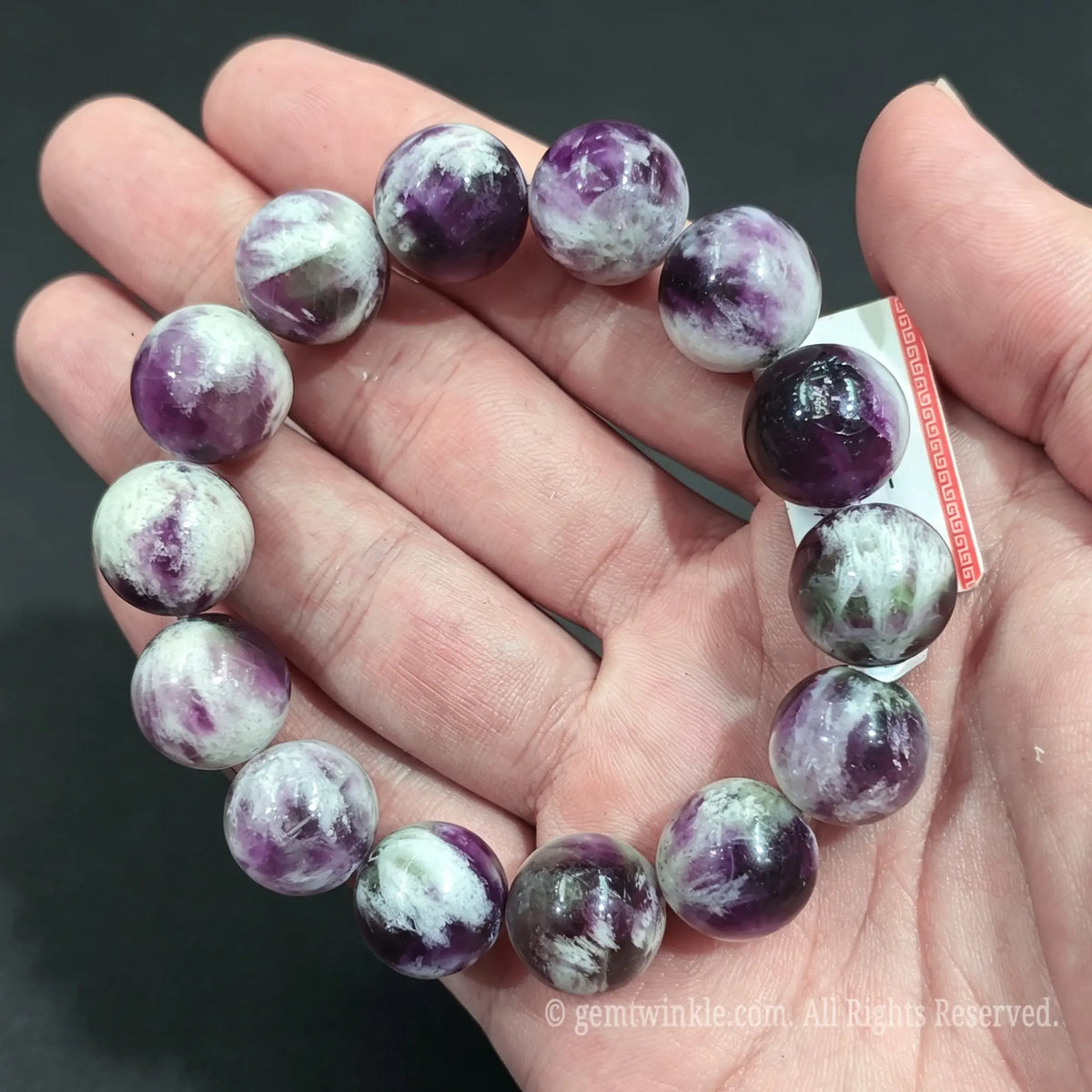 Close up view of 14-15mm feather fluorite crystal bracelet resting on palm highlighting bold mineral patterns