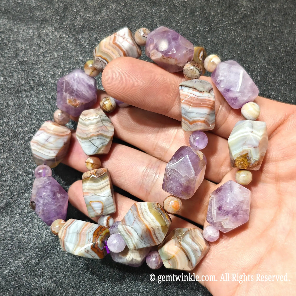 Hand holding two natural amethyst and banded agate faceted nugget stretch bracelets showing alternating bead design
