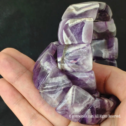 Hand holding two dreamy chevron amethyst smooth block stretch bracelets showing polished curved surfaces