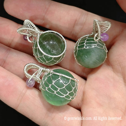 Group view of 20mm green fluorite sphere pendants held in hand highlighting silver wire cage design for jewelry making
