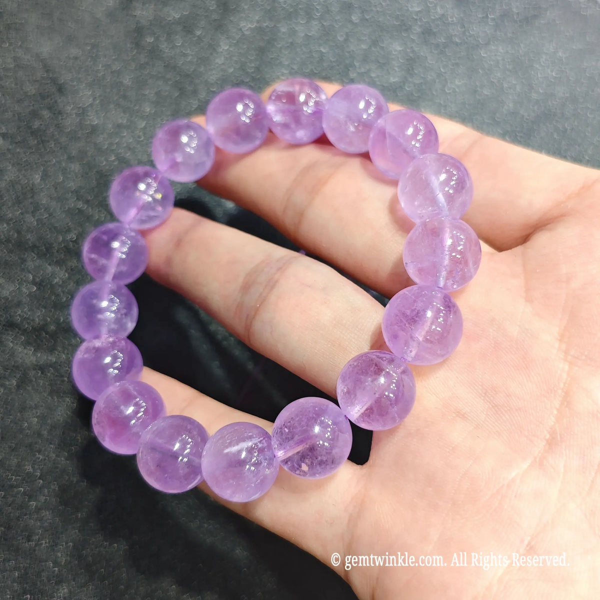 Hand worn view of a 12mm lavender amethyst stretch bracelet under soft indoor lighting[cite: 9]