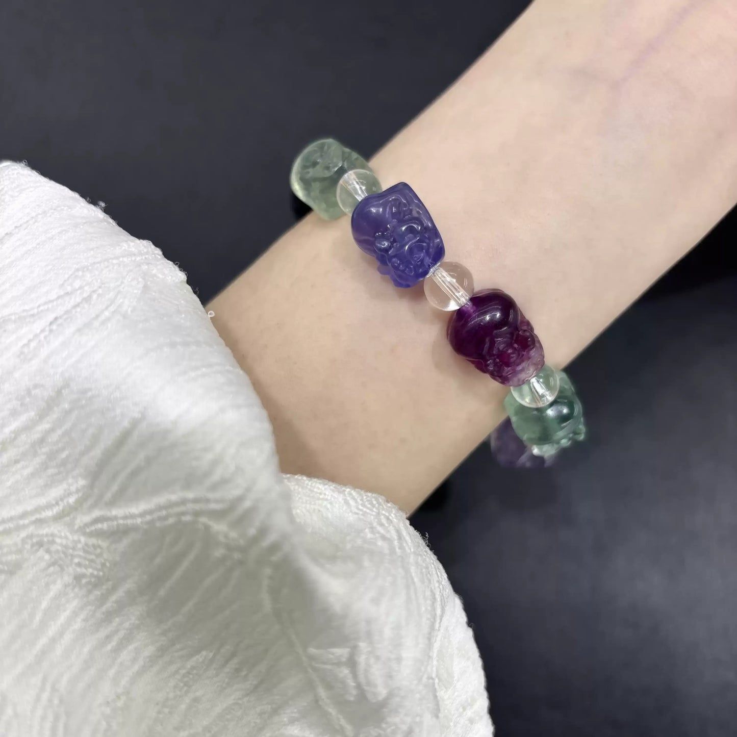 Elegant fluorite Pi Xiu bracelet worn on wrist; vibrant purple, green, yellow, blue, and pink beads visible in natural light