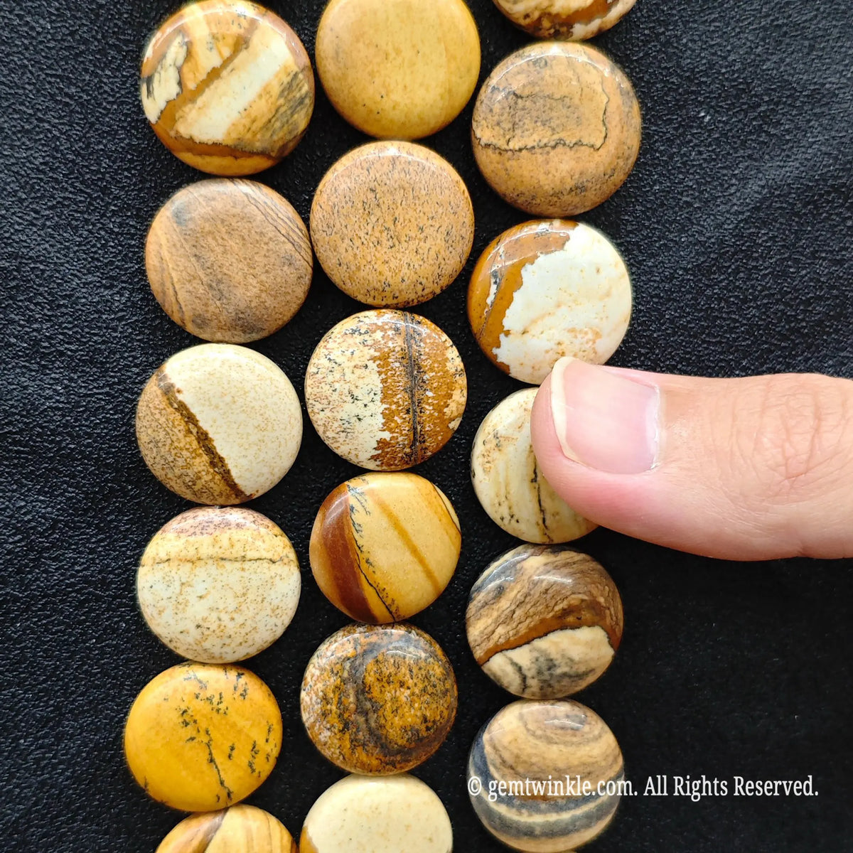 Hand showing flat round coin picture jasper loose beads highlighting desert dune landscape veining