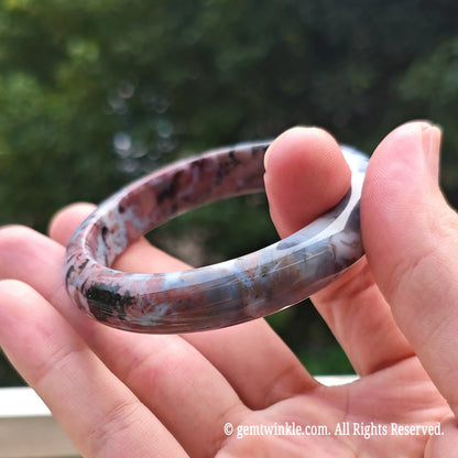 Close up view of natural pink ocean jasper bangle highlighting ice blue and dark red orbicular jasper eyes