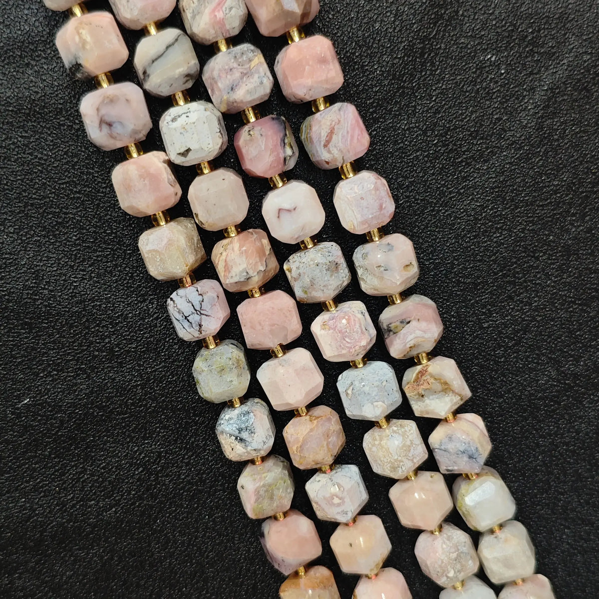 Close up of multi strands of natural pink opal soft-tumbled geometric cube beads showing overall strand layout[cite: 6]