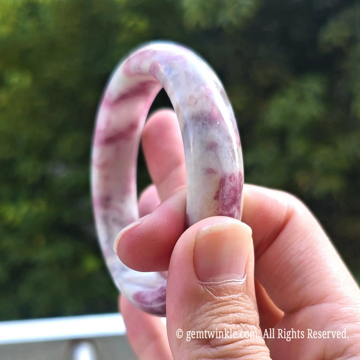 Close up profile of solid plum blossom tourmaline bangle displaying comfortable inner fit and glossy finish