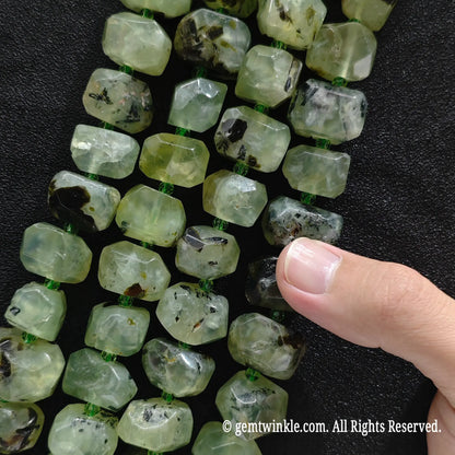 Hand holding three strands of natural green prehnite freeform faceted gemstone beads showing translucent green tone