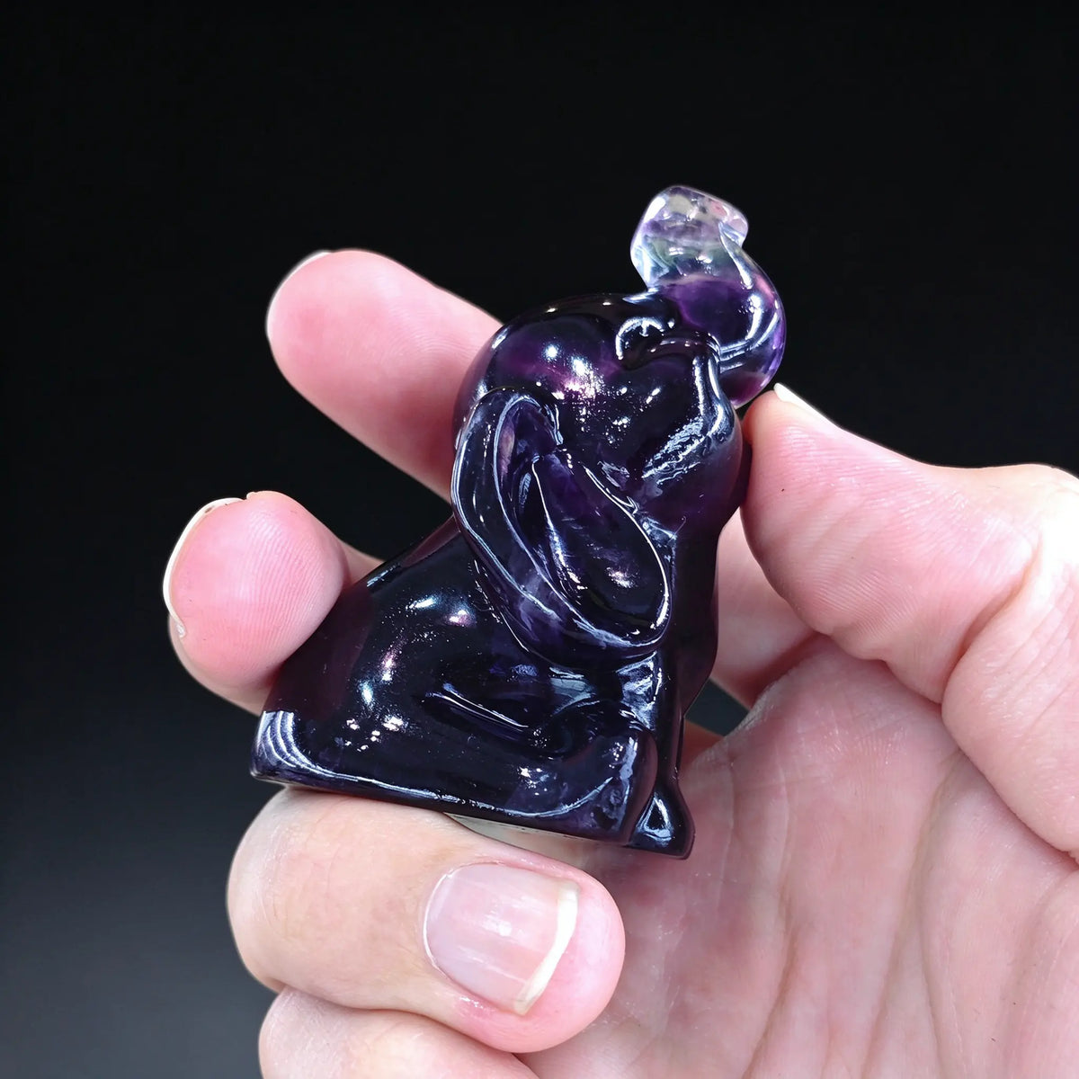 Side view of a natural rainbow fluorite lucky elephant mini sculpture showing detailed ears and smooth polished finish