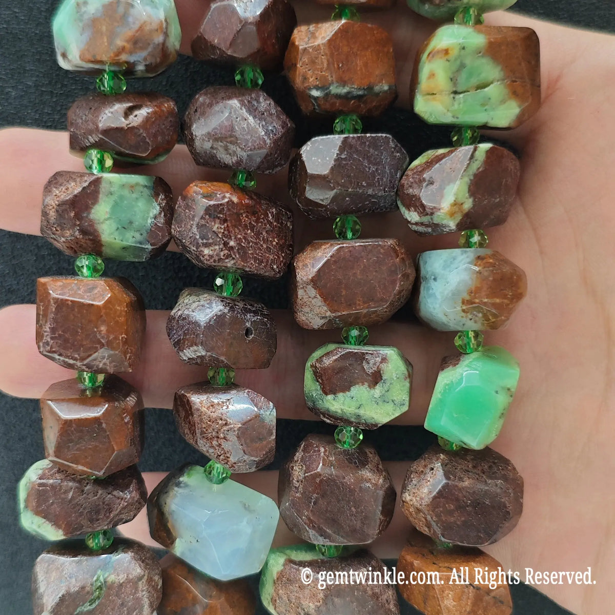 Hand holding three strands of natural green jasper matrix cut nugget beads showing brown crust and green gemstone veins