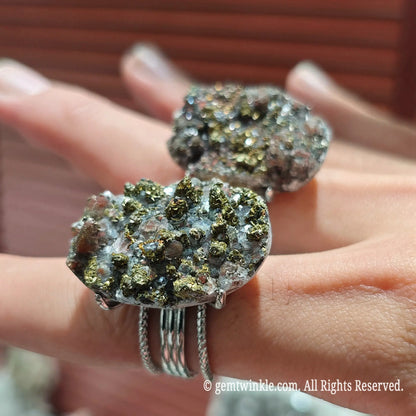 Hand wearing two oversized raw pyrite calcite mineral cluster statement rings displaying dramatic coverage