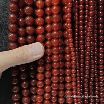 Hand holding Red Agate beads for scale