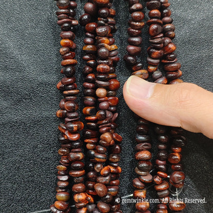 Detailed view of 75cm long red tiger eye tumbled chipped gemstone strand for jewelry DIY