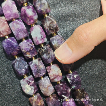 Hand displaying natural royal purple lepidolite faceted freeform beads showing rich magenta tones and pre-drilled holes