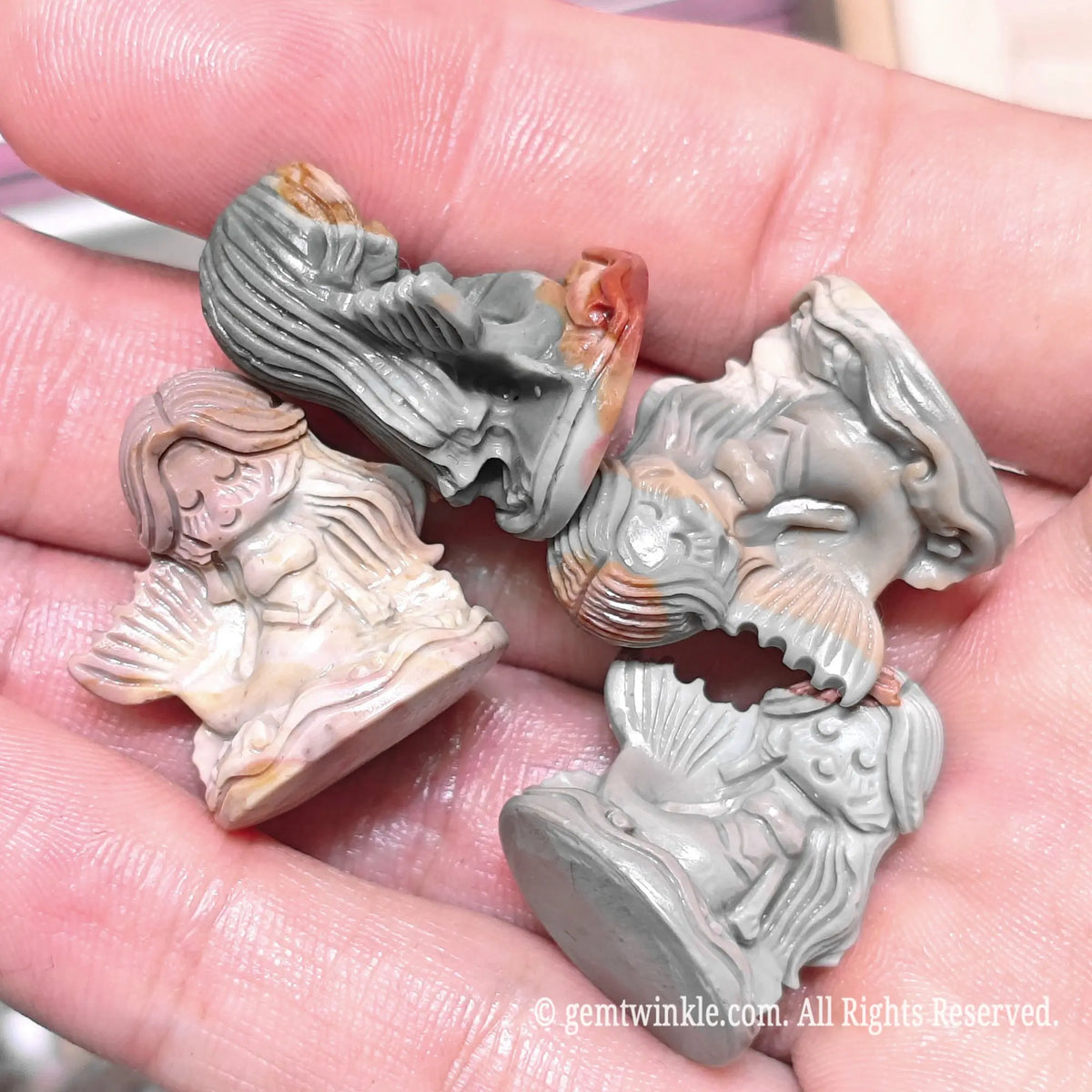 Hand holding four natural Alxa agate mermaid mini statues in varied slate gray and reddish natural patterns