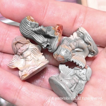 Hand holding four natural Alxa agate mermaid mini statues in varied slate gray and reddish natural patterns