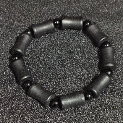 Natural matte black tourmaline barrel stretch bracelet displayed flat showing rustic cylinder beads and natural crystal striations