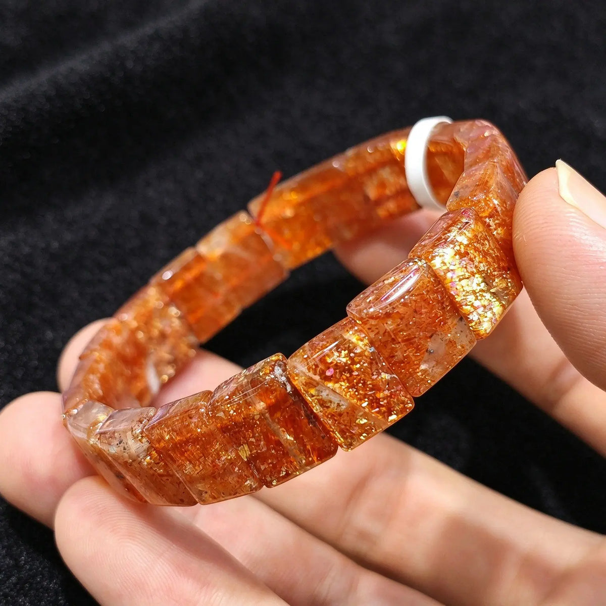 Hand wearing a high grade golden sunstone smooth block tile stretch bracelet showcasing vibrant metallic sparkles and warm color tones