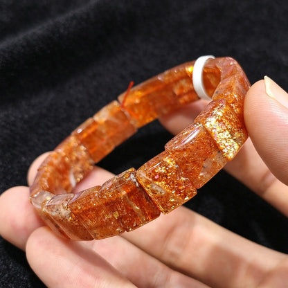 Hand wearing a high grade golden sunstone smooth block tile stretch bracelet showcasing vibrant metallic sparkles and warm color tones